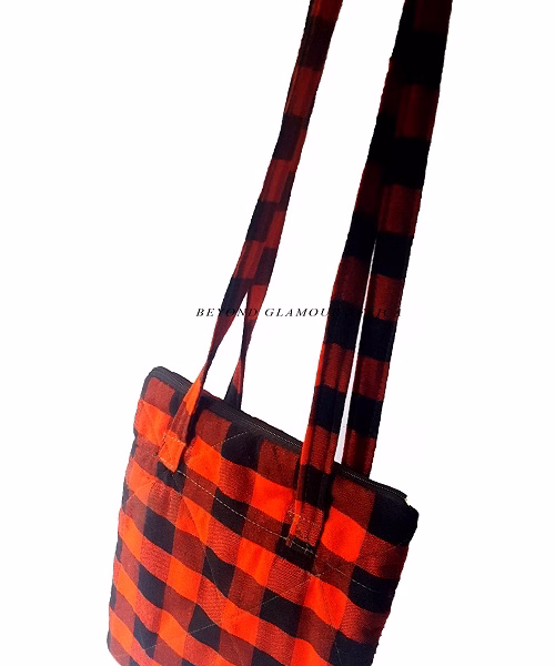 A black and red sling bag and brown wooden bracelet